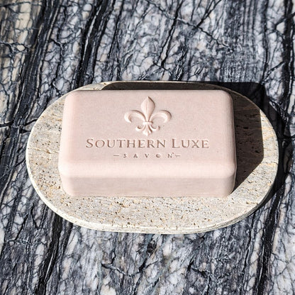 Bar of soap with 'Southern Luxe' branding on a stone soap dish against a natural background.