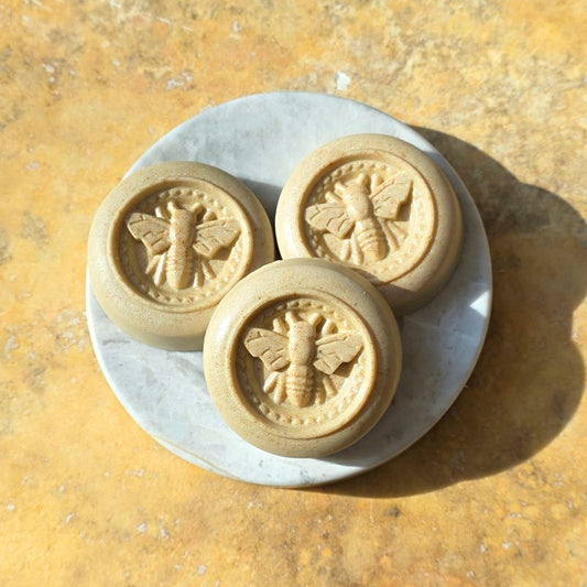 Three bee-themed cookies on a marble slab with a yellowish background