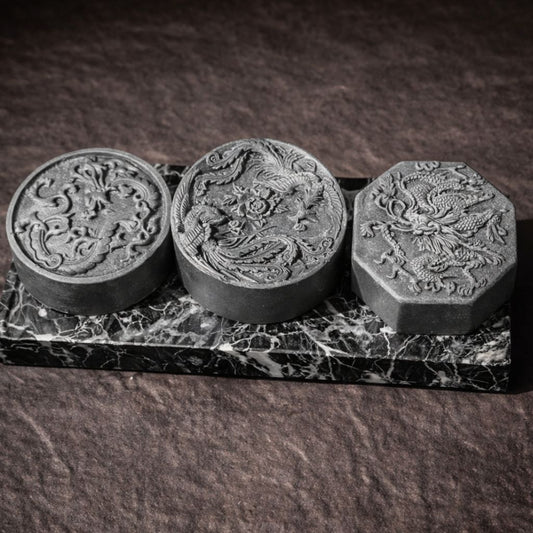 Three black stone carvings on a dark marble base